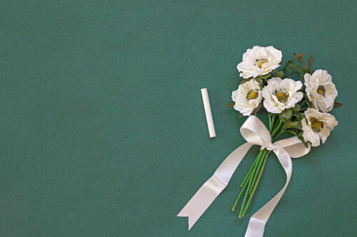 white flowers and a chalk on green chalkboard, space for text. Teacher's day